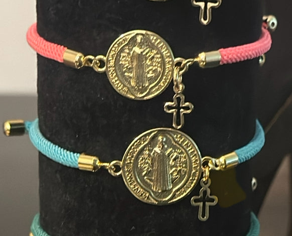 A- Pulseras de cordón con dijes de San Benito y Cruz