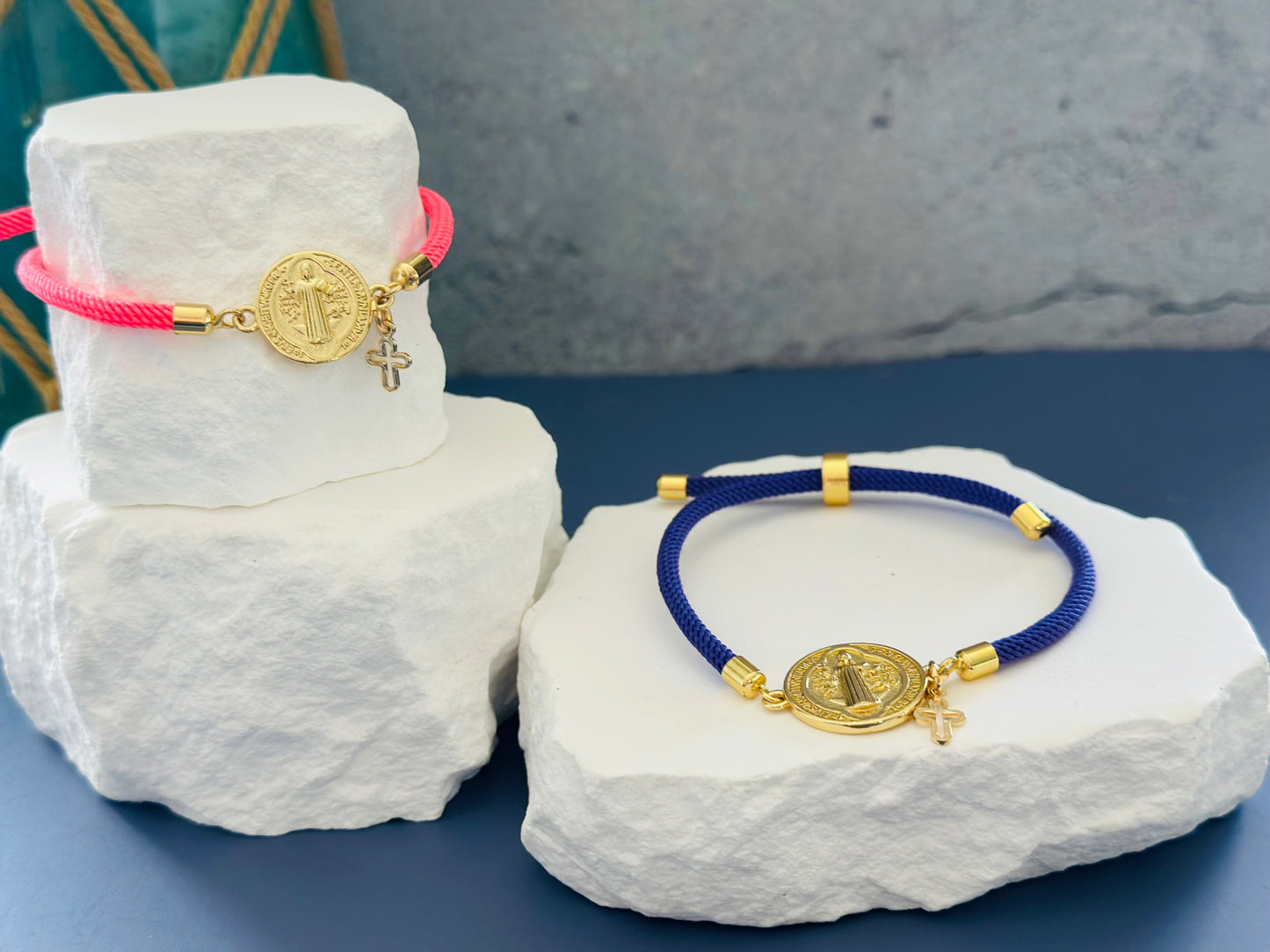 A- Pulseras de cordón con dijes de San Benito y Cruz