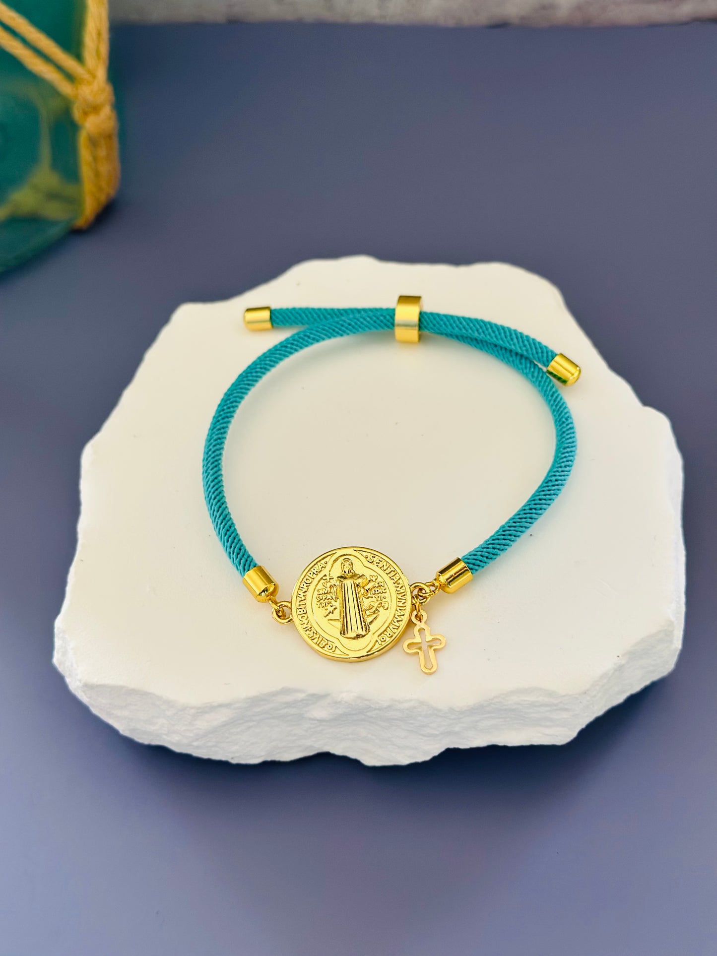 A- Pulseras de cordón con dijes de San Benito y Cruz