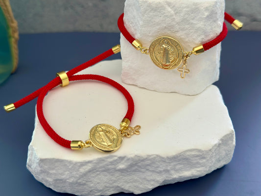 A- Pulseras de cordón con dijes de San Benito y Cruz